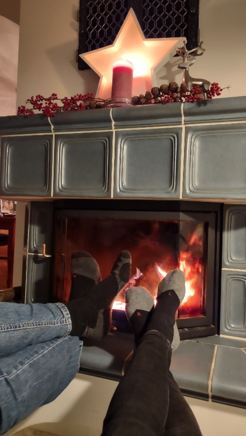 zwei Paar Füße vor einem brennenden Kamin