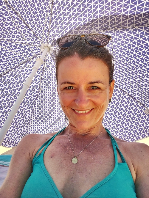 Frau im Bikini unterm Sonnenschirm am Strand