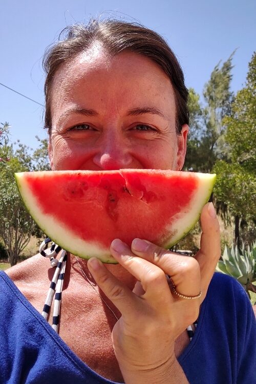 Frau mit Melonenscheibe vor dem Gesicht