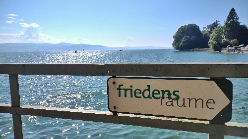 Bodensee, im Vordergrund ein Schild mit Aufschrift "friedens räume"